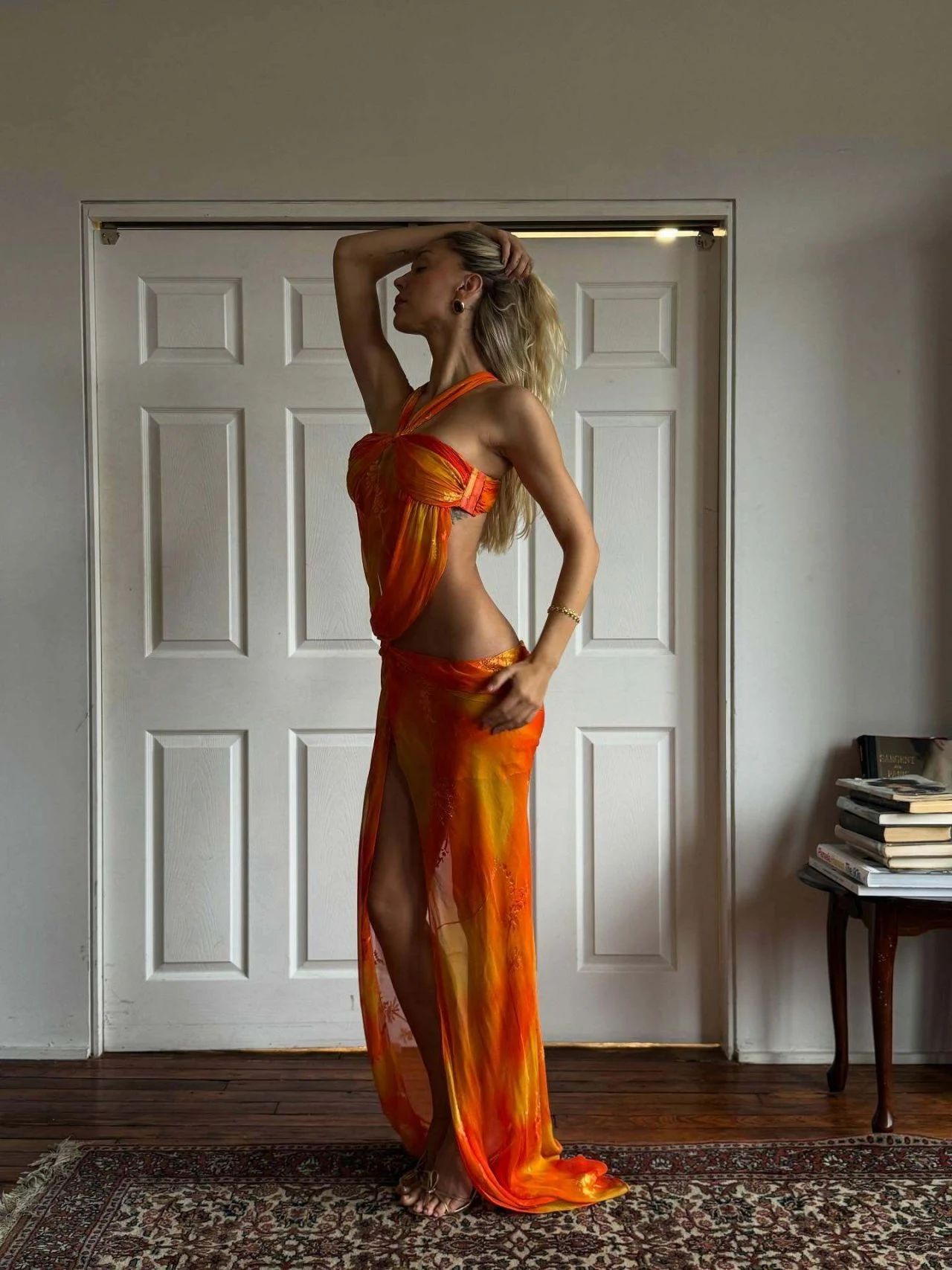 Alexis Ren barefoot in orange and yellow draped two-piece outfit for Mirror Palais