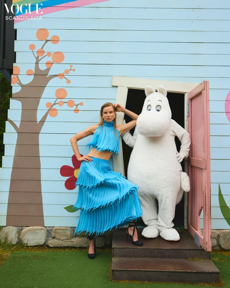 Suvi Riggs Koponen photographed in Moominworld surrounded by miniature houses for Vogue Scandinavia October 2025 issue