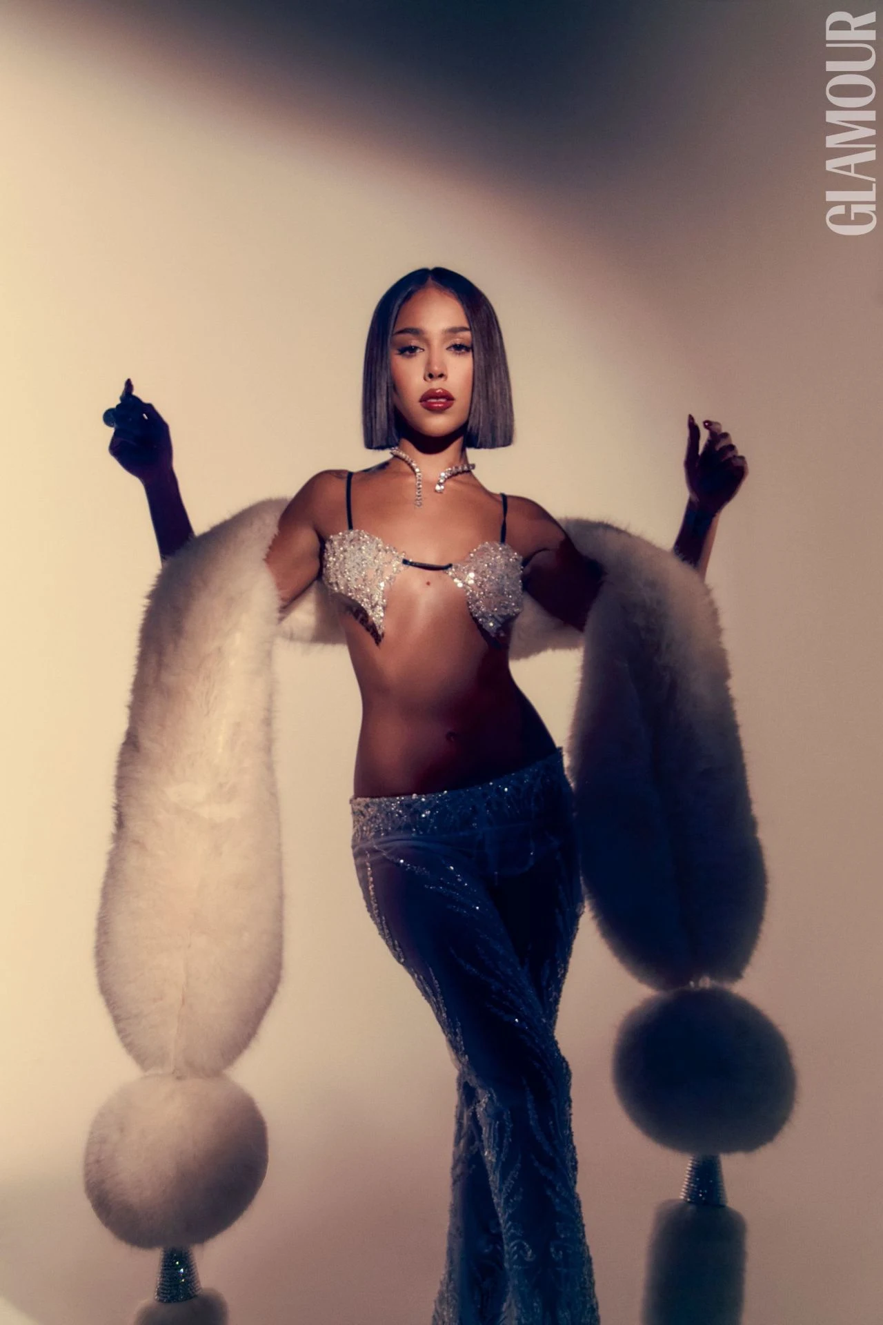 Danna Paola in embellished bra top, glitter pants, and white fur stole