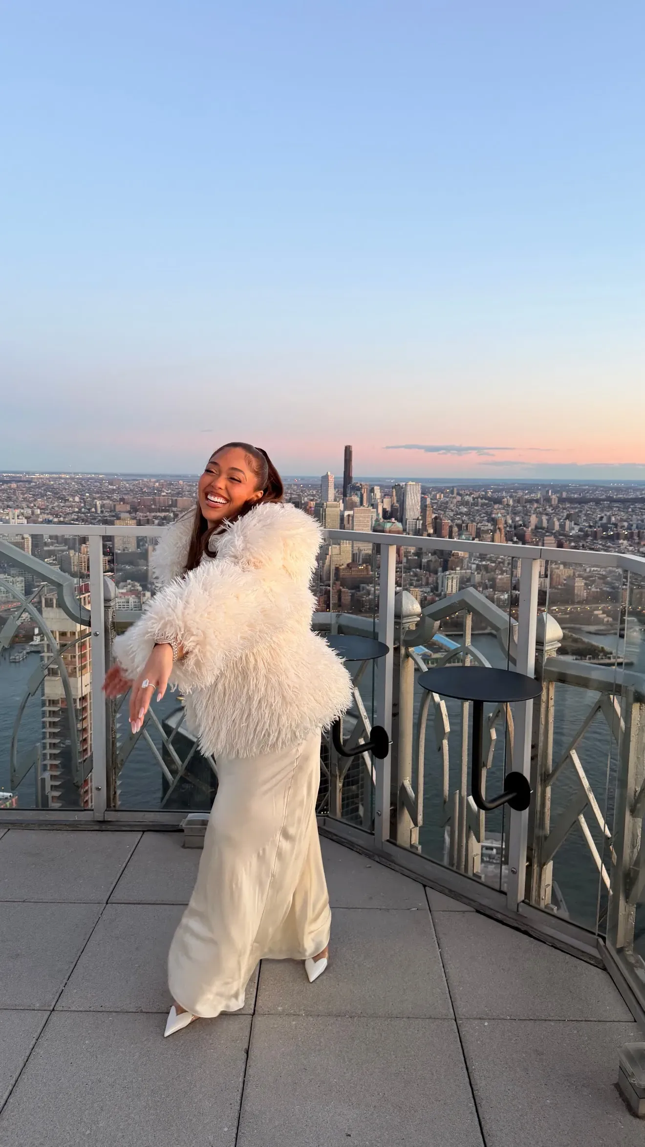 Jordyn Woods in a white shearling coat and cream gown during her Christmas engagement in New York City