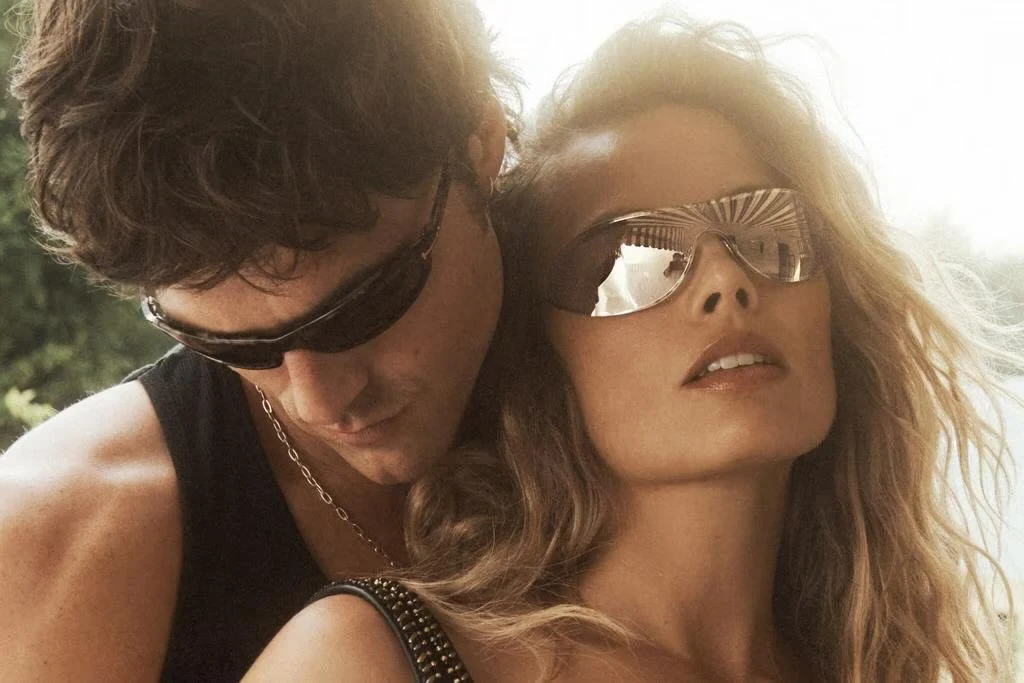 Jacob Elordi wears a Supreme x Hanes tank top; Tom Ford sunglasses; Cartier earrings and necklace. Margot Robbie wears a Versace bralette; Tom Ford sunglasses.